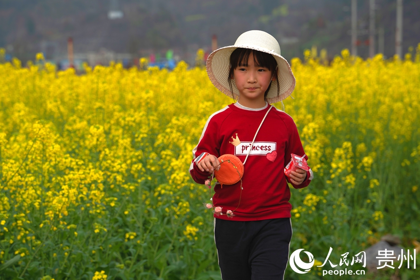 游客站在田坎上與盛放的油菜花合影。人民網(wǎng) 陽茜攝