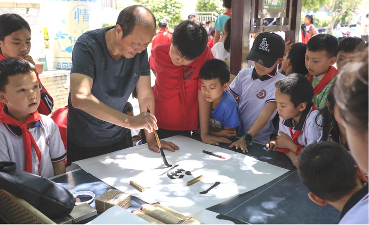 圖為黔西南州老年書畫研究會(huì)會(huì)員現(xiàn)場(chǎng)給同學(xué)們傳授講解書法。