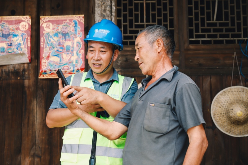 1 圖為中國移動貴州公司網(wǎng)絡(luò)建設(shè)人員正拿著手機為村民們進行演示。.jpg