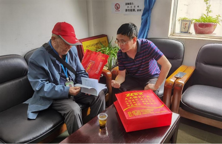 2 圖為興仁市委組織部副部長、市委老干局局長譚巍向退休干部覃登濤講解長護(hù)險政策。