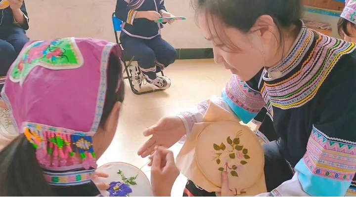 圖為織秀老師現(xiàn)場對學(xué)生刺繡進行指導(dǎo)。