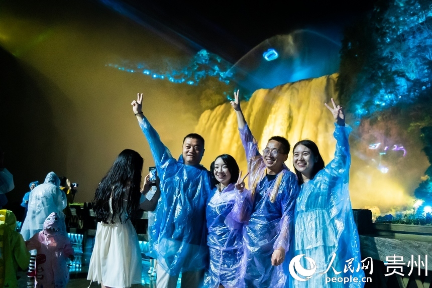 游客在夜間黃果樹前打卡拍照。人民網(wǎng)記者 涂敏攝