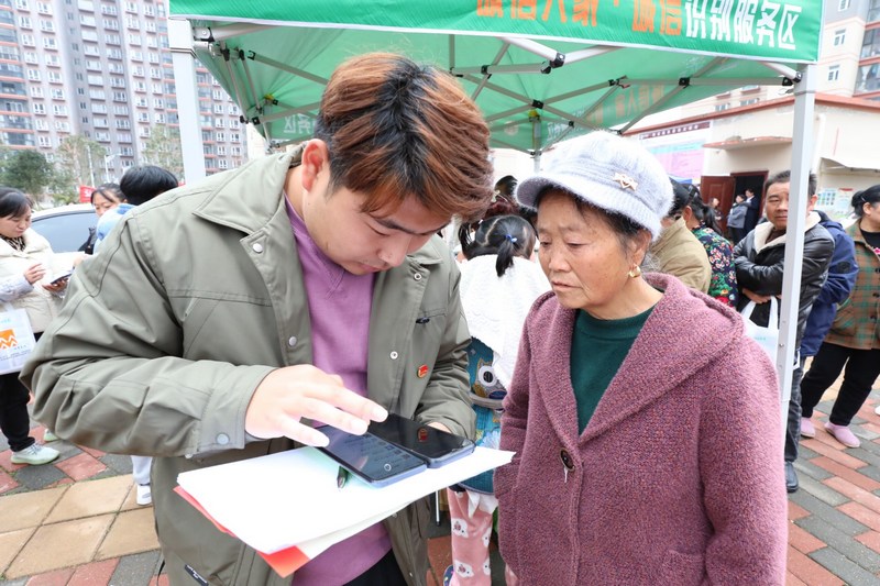(3)2023年12月9日，清鎮(zhèn)市鄉(xiāng)愁社區(qū)云夢小鎮(zhèn)。圖為活動現(xiàn)場志愿者幫小區(qū)居民領(lǐng)取誠信消費(fèi)券。（任芳靚 攝）.jpg
