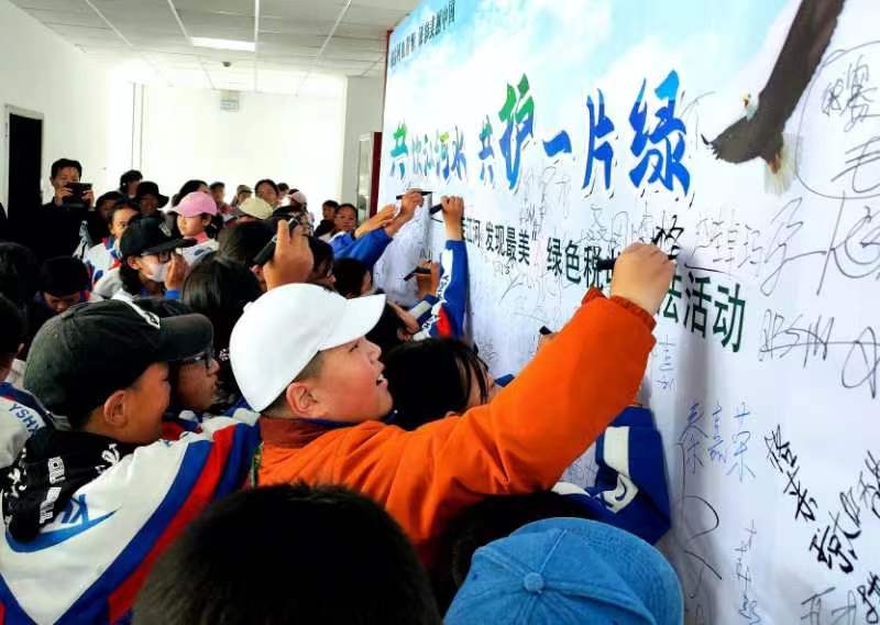 小孩子們在“行走江河發(fā)現(xiàn)最美”倡議書上簽字。馬國柱攝