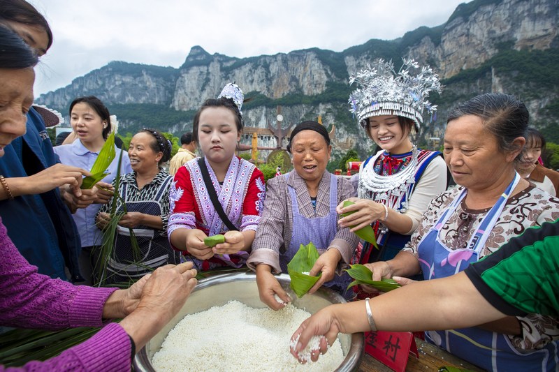 6月7日，貴州省畢節(jié)市黔西市新仁苗族鄉(xiāng)化屋村，村民們和游客包粽子。