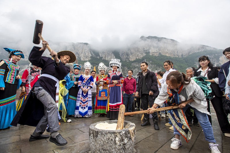 6月7日，貴州省畢節(jié)市黔西市新仁苗族鄉(xiāng)化屋村，村民們和游客打糍粑。