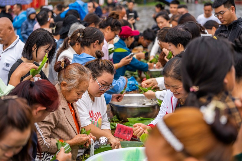 6月7日，游客在貴州省畢節(jié)市黔西新仁苗族鄉(xiāng)化屋村體驗包粽子。