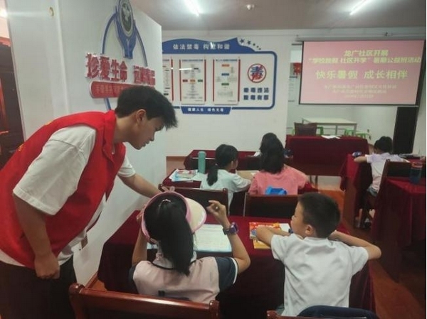 大學(xué)生志愿者正在輔導(dǎo)督促學(xué)生們做暑假作業(yè)。