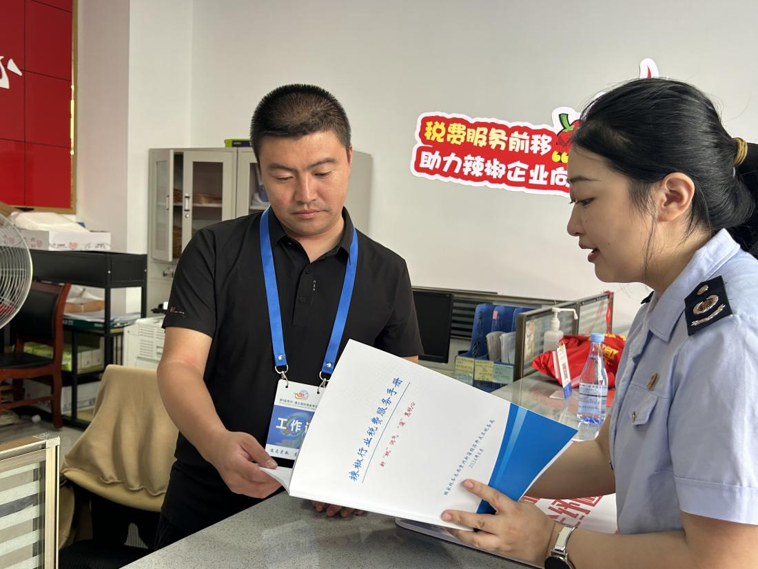 稅務(wù)干部為辣椒企業(yè)送上辣椒行業(yè)稅費(fèi)服務(wù)手冊(cè)。周萬(wàn)青攝