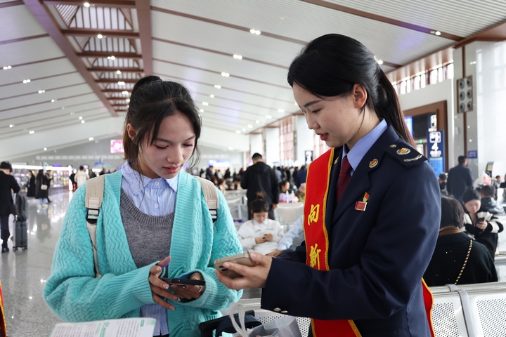 在高鐵站候車大廳稅務(wù)干部向旅客宣傳“電子客票”并輔導(dǎo)開具。何博攝