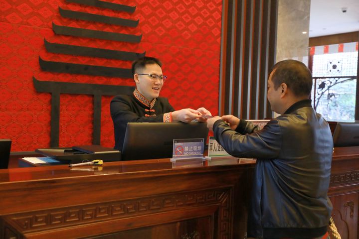萬里將房卡遞給房客。楊潔茹攝