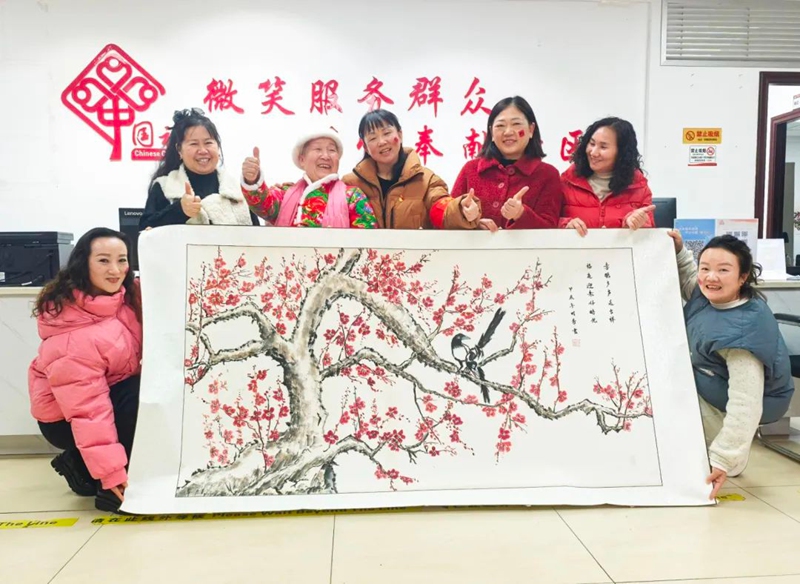 劉阿姨（左三）向社區(qū)工作人員送來親手畫的《鳴春圖》繪畫作品。1