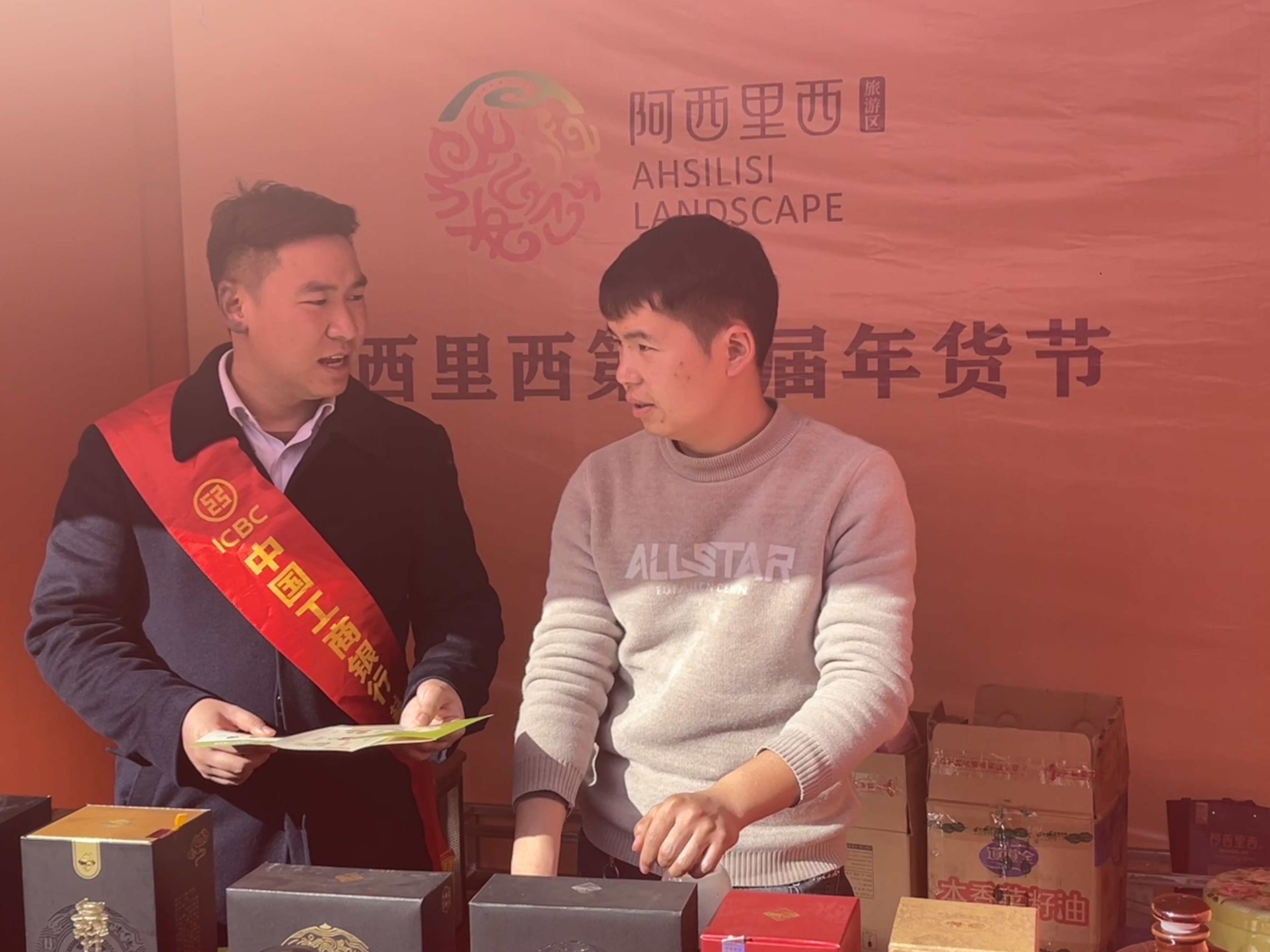 工作人員向阿西里西年會節(jié)商戶宣傳工行普惠貸款、普及金融知識。