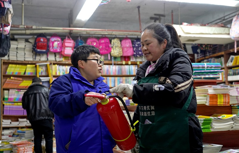 2025年2月17日，貴州省畢節(jié)市納雍縣城一書(shū)店，檢查組成員在指導(dǎo)書(shū)店員工使用滅火器。楊英攝