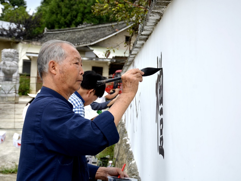 組織志愿者為村莊繪制文化墻。