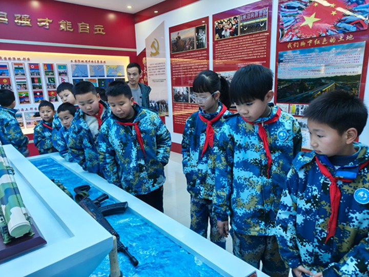 學(xué)生們?cè)诶蠋煹膸ьI(lǐng)下參觀學(xué)校的軍事國(guó)防展覽廳。