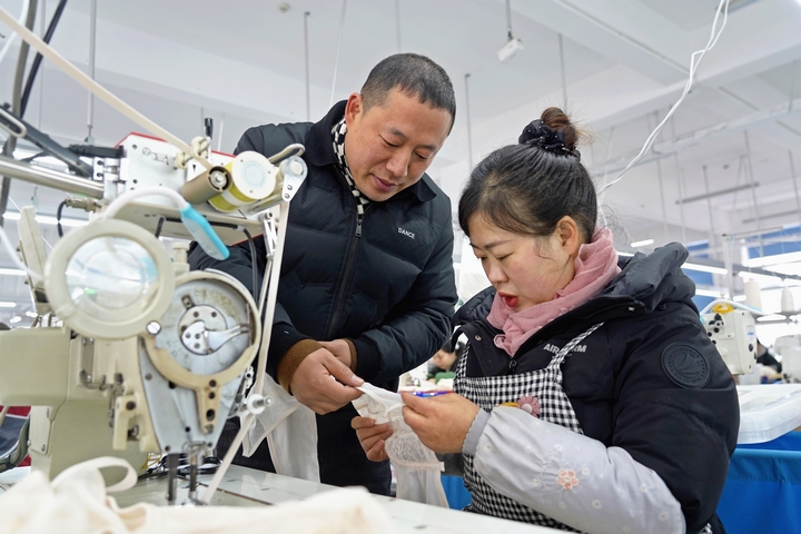 2025年2月25日，位于貴州省畢節(jié)市納雍縣工業(yè)園區(qū)的貴州博澤服裝有限公司生產(chǎn)車(chē)間，車(chē)間負(fù)責(zé)人與員工一起討論產(chǎn)品制作工藝。 楊英 攝.jpg