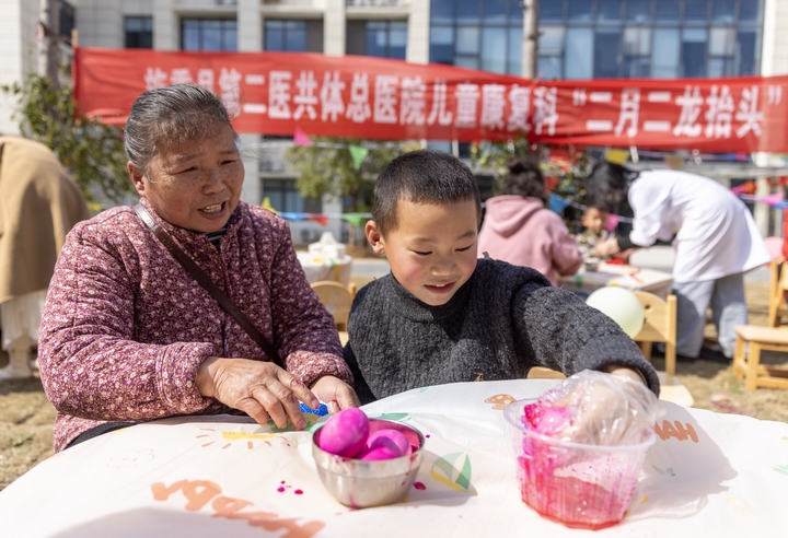 2025年2月28日，貴州省黔東南苗族侗族自治州施秉縣第二醫(yī)共體總醫(yī)院兒童康復(fù)科，家長(zhǎng)在指導(dǎo)孩子染紅蛋。（磨桂賓 攝） (1).jpg