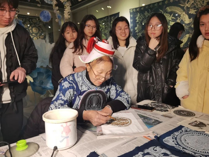 省級蠟染技藝傳承人羅文珍現(xiàn)場展示畫蠟技藝，吸引眾多觀眾駐足觀看并參與體驗.jpg