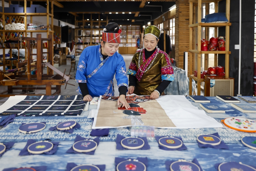 龍祿穎（右）與公司員工在手工刺繡車間交流苗繡新產(chǎn)品的設(shè)計理念。