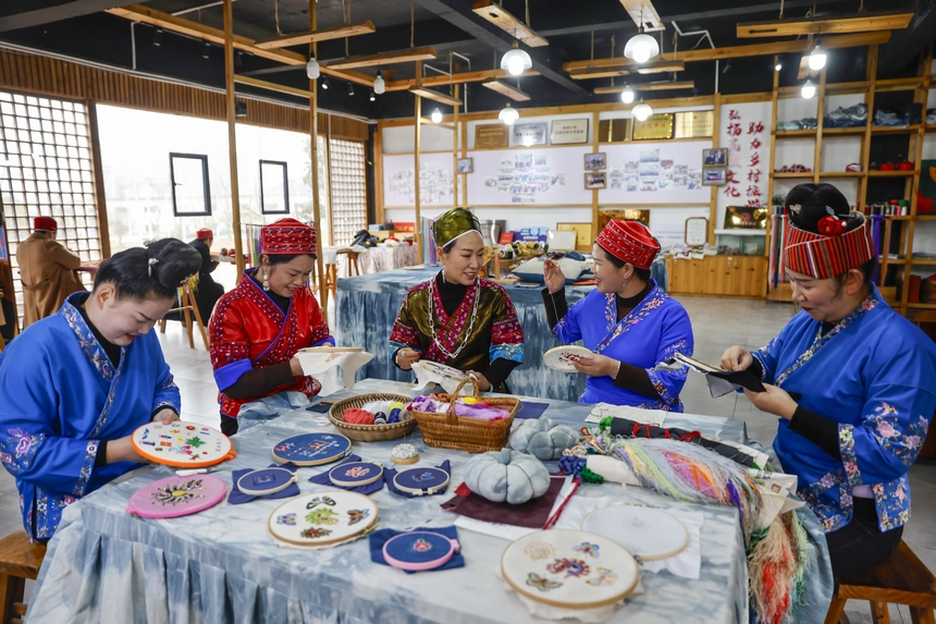 龍祿穎（中）與公司員工在手工刺繡車間刺繡。