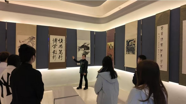 8、工作室主持人潘瑜為觀眾介紹展廳校史部分書畫展.jpg