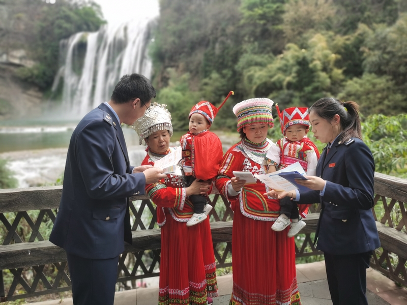 黃果樹大瀑布景區(qū)，安順市鎮(zhèn)寧縣稅務局干部正在為少數(shù)民族納稅人講解政策。舒開培攝