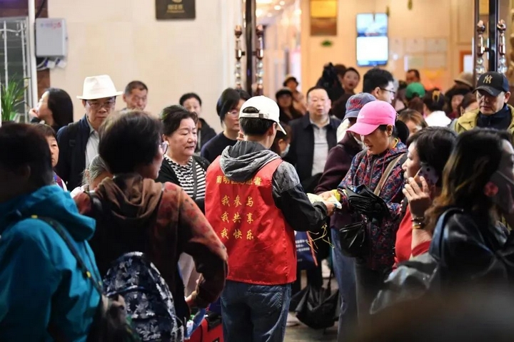 3 社區(qū)志愿者正在為出行的游客發(fā)放一次性雨衣.jpg
