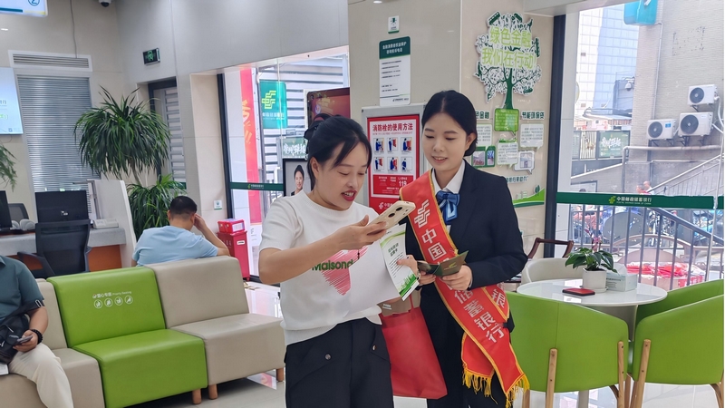 工作人員向網(wǎng)點(diǎn)等候客戶宣傳“陽光信貸”。