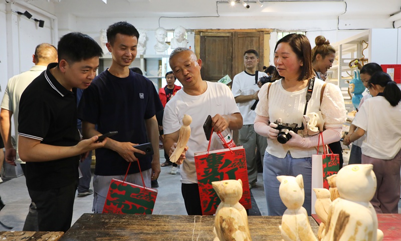游客們駐足欣賞鄉(xiāng)土氣息濃郁的藝術(shù)作品。陳桂良攝