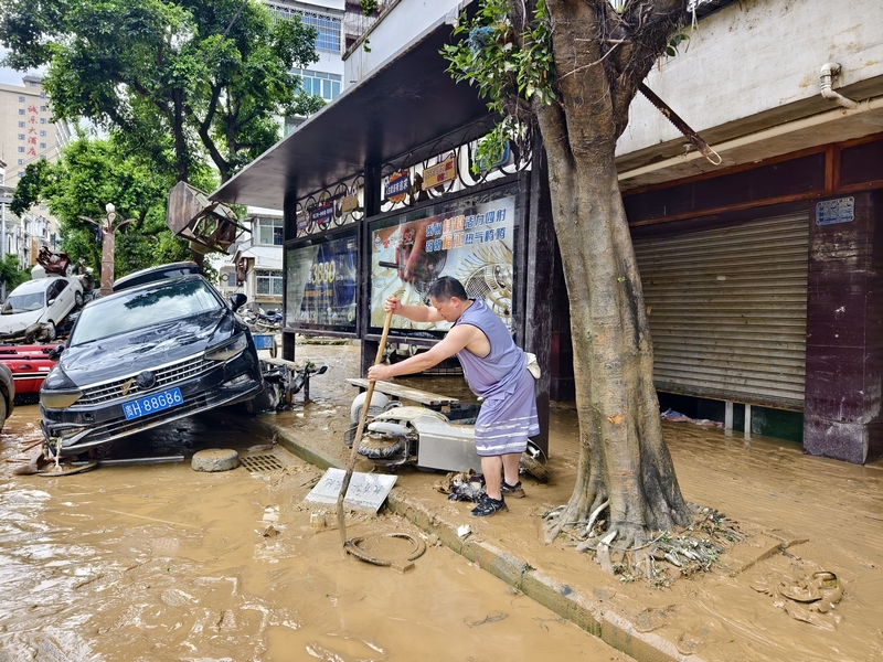 榕江縣稅務(wù)局黨委委員、副局長陳風(fēng)在清掃縣城主大街淤泥。