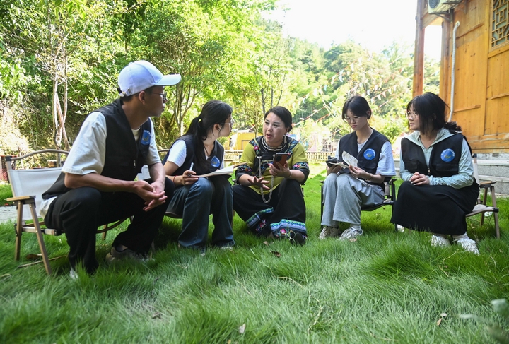 7月4日，在盤信鎮(zhèn)大灣苗寨，銅仁學(xué)院的學(xué)生在和當(dāng)?shù)孛缱宕迕窳私饷褡逦幕?。謝慧芳攝.JPG