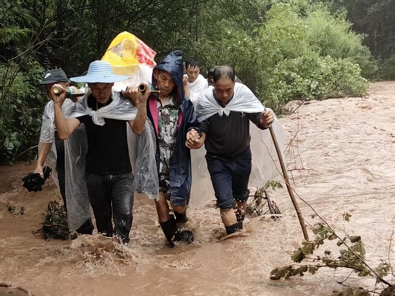 暴雨中村民抬傷者蹚過渾濁積水路。習(xí)水縣融媒體中心供圖